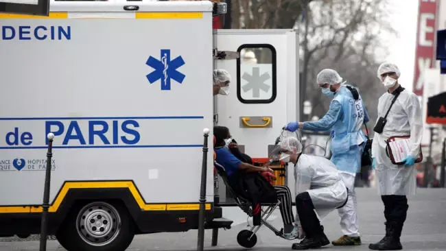 French rescue workers evacuate a patient in Paris on March 20, 2020, as France faces an aggressive progression of the coronavirus disease COVID-19.